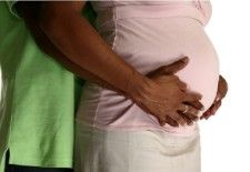 Attractive African American expecting parents over white background.