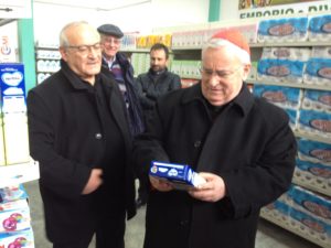 CARD BASSETTI CON PARROCO DON REGNI MENTRE OSSERVA UN PRODOTTO ALIMENTARE ALL'INTERNO DELL'EMPORIO CARITAS
